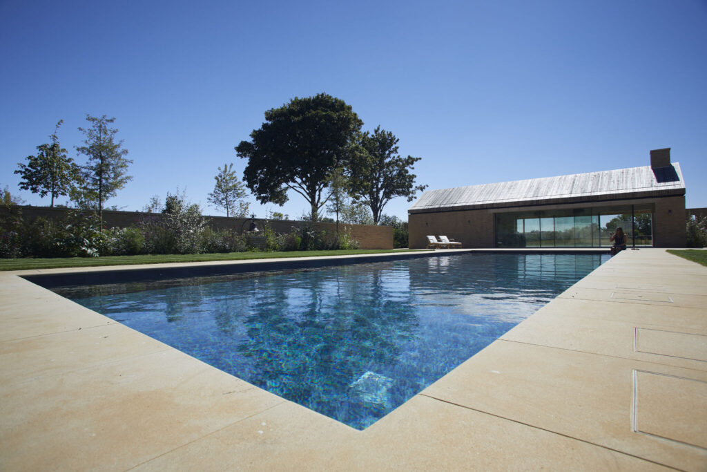 Image of a swimming pool with house and tree in background